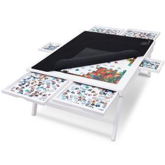 a white table with four pieces of artwork on it and a black cover over the top