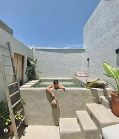 a man sitting in the middle of a pool with stairs leading up to his back