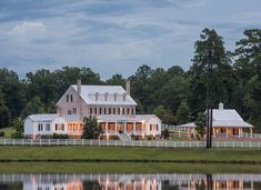 a large white house sitting on top of a lush green field next to a lake