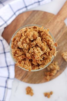 a glass filled with granola sitting on top of a wooden cutting board