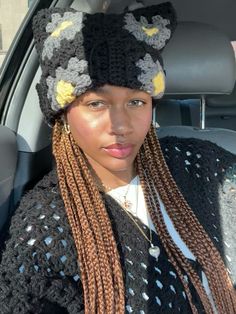 a woman with long braids wearing a knitted hat in the back seat of a car