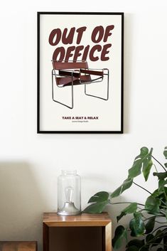 a poster hanging on the wall above a table with a plant in front of it