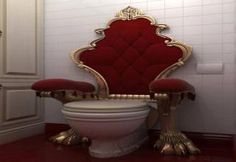 a red chair sitting on top of a white toilet next to a tall golden throne