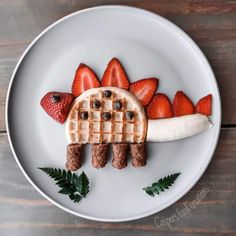 a plate with waffles, bananas and strawberries on it that is shaped like a turtle