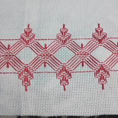 a red and white cross stitched design on a piece of cloth