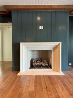 an empty room with a fireplace and wood flooring in the center is painted blue