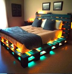 a bed made out of pallets with lights on the sides and pillows in it