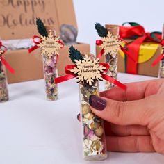 a hand holding a bottle filled with candy and candies next to other small packages