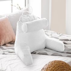 a white stuffed animal laying on top of a bed next to pillows and a basket