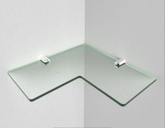 the corner of a glass shelf is shown with two hooks on one side and an upside down mirror on the other