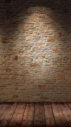 an empty room with a brick wall and wooden floor, lit by a spot light