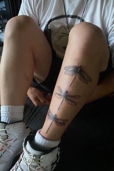 a person sitting on the ground with some tattoos on their legs