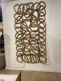 a sculpture made out of metal rings on display in a room with people standing around