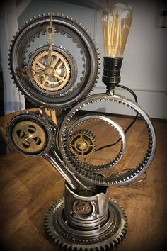 a clock made out of gears on top of a wooden table next to a light bulb