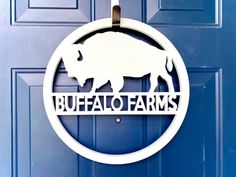 a sign that says buffalo farms hangs on the front door of a blue door,