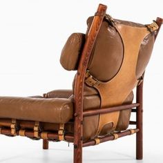 a brown leather reclining chair with wooden frame and arm rests on a white background