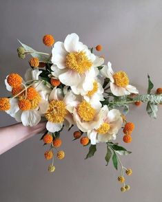 white and yellow flowers are being held by someone's hand