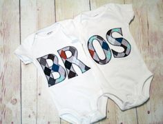 two baby onesuits with the word bros printed on them, sitting next to each other