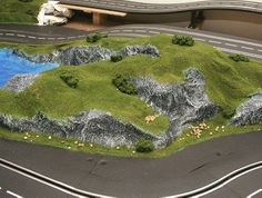 a model road with grass and rocks on the sides, next to a highway sign that says manicstots