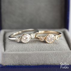 two gold rings with white diamonds are sitting in a box