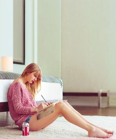 a woman sitting on the floor writing in her notebook