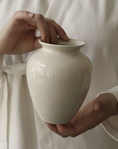 a person holding a white vase in their hands