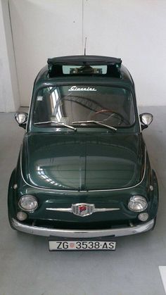 an old green car parked in a garage