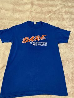 D.A.R.E. Dare Officially Licensed Keeping Kids Off Drugs Blue T-Shirt S Blue Band Merch T-shirt, Blue Band Merch T-shirt With Logo Print, Blue Band Merch T-shirt With Logo, Blue Graphic Tee T-shirt With Slogan, 90s Style Blue T-shirt With Text Print, 90s Blue Tops With Graphic Print, Blue Slogan Graphic Tee, Blue Graphic Tee With Slogan, Retro Blue Tops With Letter Print