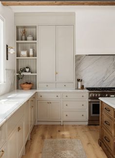 a large kitchen with white cabinets and marble counter tops, along with wooden flooring