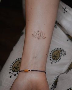 a woman's wrist with a small flower tattoo on the left side of her arm