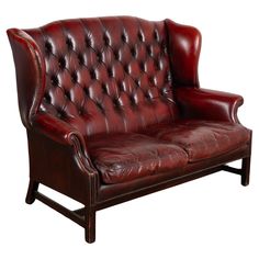 a red leather couch with wooden legs and nail polishing on the armrests