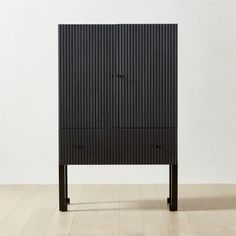 a black cabinet sitting on top of a hard wood floor next to a white wall