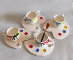 four cups and saucers with paint splatters painted on them, sitting on top of each other