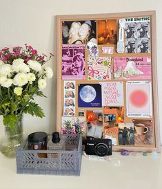 a vase filled with white flowers next to a framed photo and some pictures on a wall