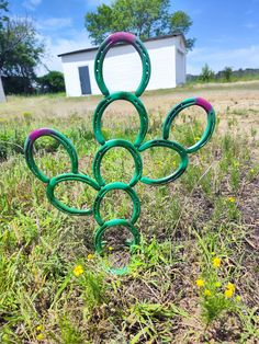 a metal sculpture in the middle of a field with circles on it's sides