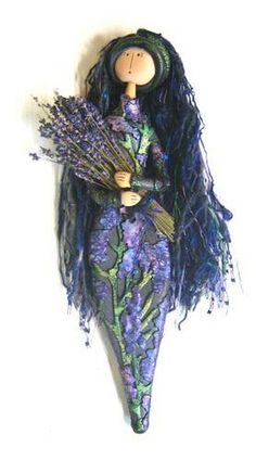 a doll with long black hair and purple flowers on her body is holding a bunch of lavenders