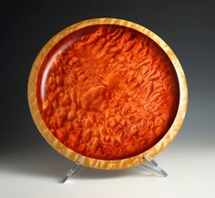 an orange plate sitting on top of a metal stand in front of a gray background