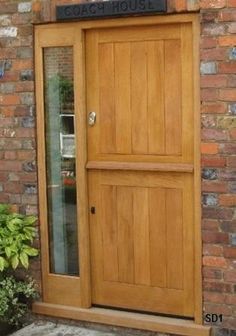 a wooden door sitting in front of a brick wall next to a potted plant