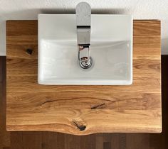 a white sink mounted to the side of a wooden counter with a metal faucet