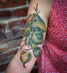 a woman's arm with green leaves on it