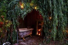 an outdoor bathtub in the middle of a garden with lights on it's sides