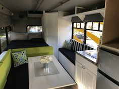 the interior of a camper with couches, tables and kitchenette in it