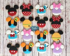 mickey and minnie mouse cupcakes are arranged on a wooden table with the top one decorated in different colors