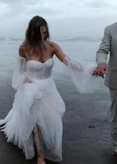 a man and woman dressed in white walking on the beach