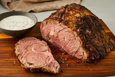 a large piece of meat sitting on top of a cutting board next to a knife and fork