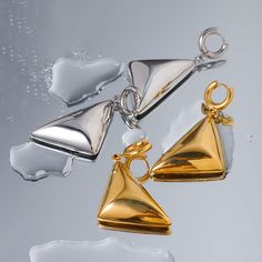 Meet your new statement piece: the Vanguard Gold Earrings. These sleek, geometric beauties are designed to turn heads and elevate your style game. Crafted with a high-shine 18 karat gold finish, these earrings feature a bold triangular design that dangles elegantly, creating a modern and sophisticated look. The unique pyramid shape of the earrings adds an edgy flair, making them perfect for both casual and formal outfits. Notice how they catch the light beautifully, highlighting the clean lines Modern Single Triangle Earring, Elegant Triangle Metal Earrings, Gold Triangle Metal Earrings, Triangle Gold Metal Earrings, Modern Triangle Gold Hoop Earrings, Modern Triangle Metal Earrings, Modern Triangle Earrings For Party, Elegant Triangle Earrings For Formal Occasions, Modern Triangle Party Earrings