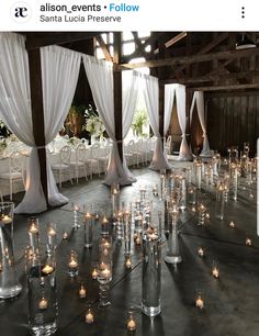 a room filled with lots of tables covered in white draping and lit candles