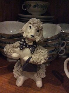 a ceramic sheep figurine sitting on top of a table next to plates and bowls