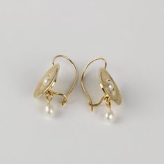 These unique shiny gold pearl earrings are handmade of yellow 14k solid gold and freshwater pearls. They have a hammered texture and a shiny finish. The white pearls are smooth and beautiful. The combination of the feminine pearls and the hammered gold is harmonious and eye catching. They can be a perfect match for a pearl necklace, or a gold necklace. These earrings are classy and timeless, earrings you will enjoy wearing for many years. Total length of the earrings is 3 cm = 1.18 inch Earrings Hallmarked Yellow Gold Pearl Drop Earrings, 14k Gold Pearl Earrings With Pearl Pendant, 14k Gold Drop Pearl Earrings With Pearl Charm, Gold Hammered Elegant Pearl Earrings, Elegant Hammered Gold Pearl Earrings, Elegant Gold Hammered Pearl Earrings, Hand Forged Gold Pearl Earrings, 14k Yellow Gold Drop Pearl Earrings, Elegant Hand Forged Gold Pearl Earrings