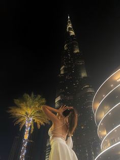 a woman standing in front of a tall building at night